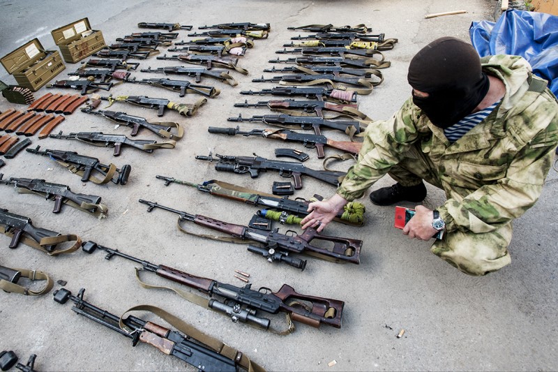 Антиправительственный активист демонстрирует оружие, которое, как он утверждает, было изъято у украинских солдат после рейда в городе Горловка. 