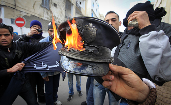 Протестующие сжигают фуражку полицейского в&nbsp;центре Туниса. Январь 2011 года

