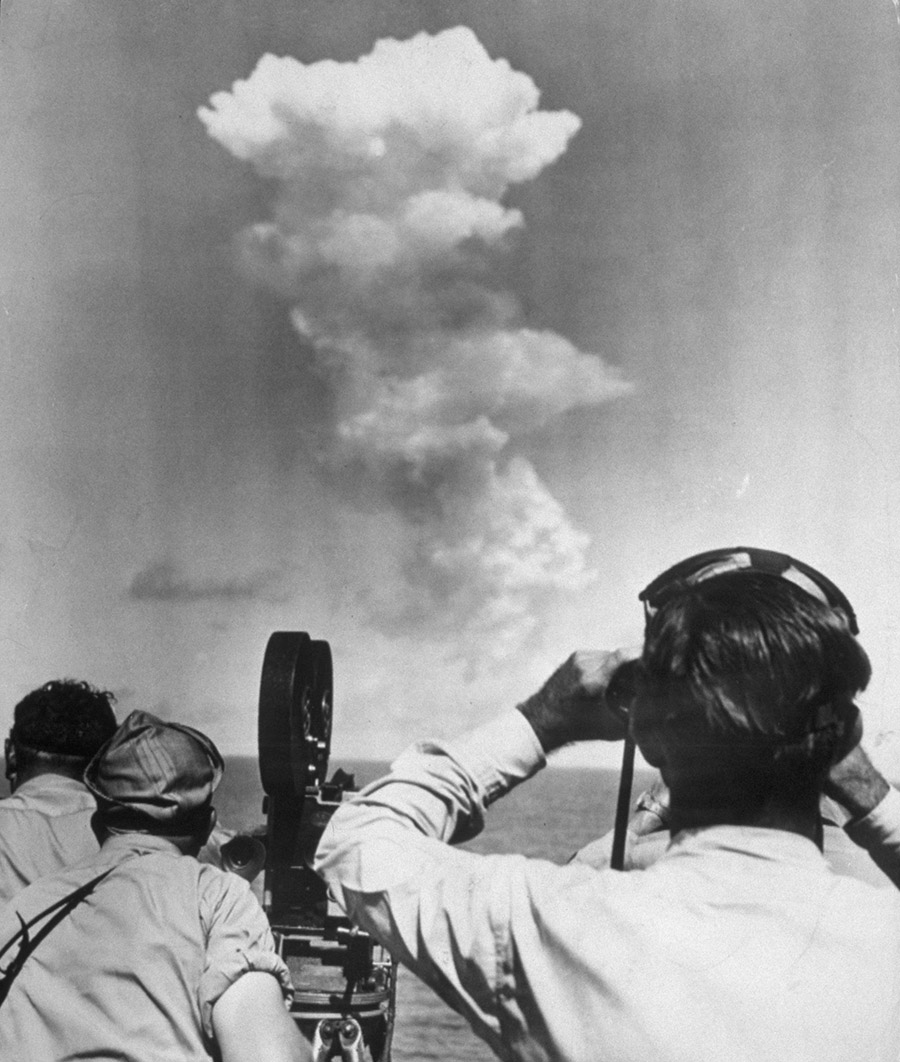 На фото: люди на палубе американского корабля Mount McKinley наблюдают грибовидное облако, поднявшееся из лагуны Бикини через несколько секунд после взрыва атомной бомбы. Июль 1946 года.

Для этого подходили атоллы (корралловые острова) архипелага Маршалловы острова. С 1914 года они были под контролем Японии, а в 1944-м перешли под контроль США; в 1947 году вместе с другими тихоокеанскими владениями Токио они были включены в подопечную территорию Тихоокеанские острова, которая находилась под управлением Вашингтона