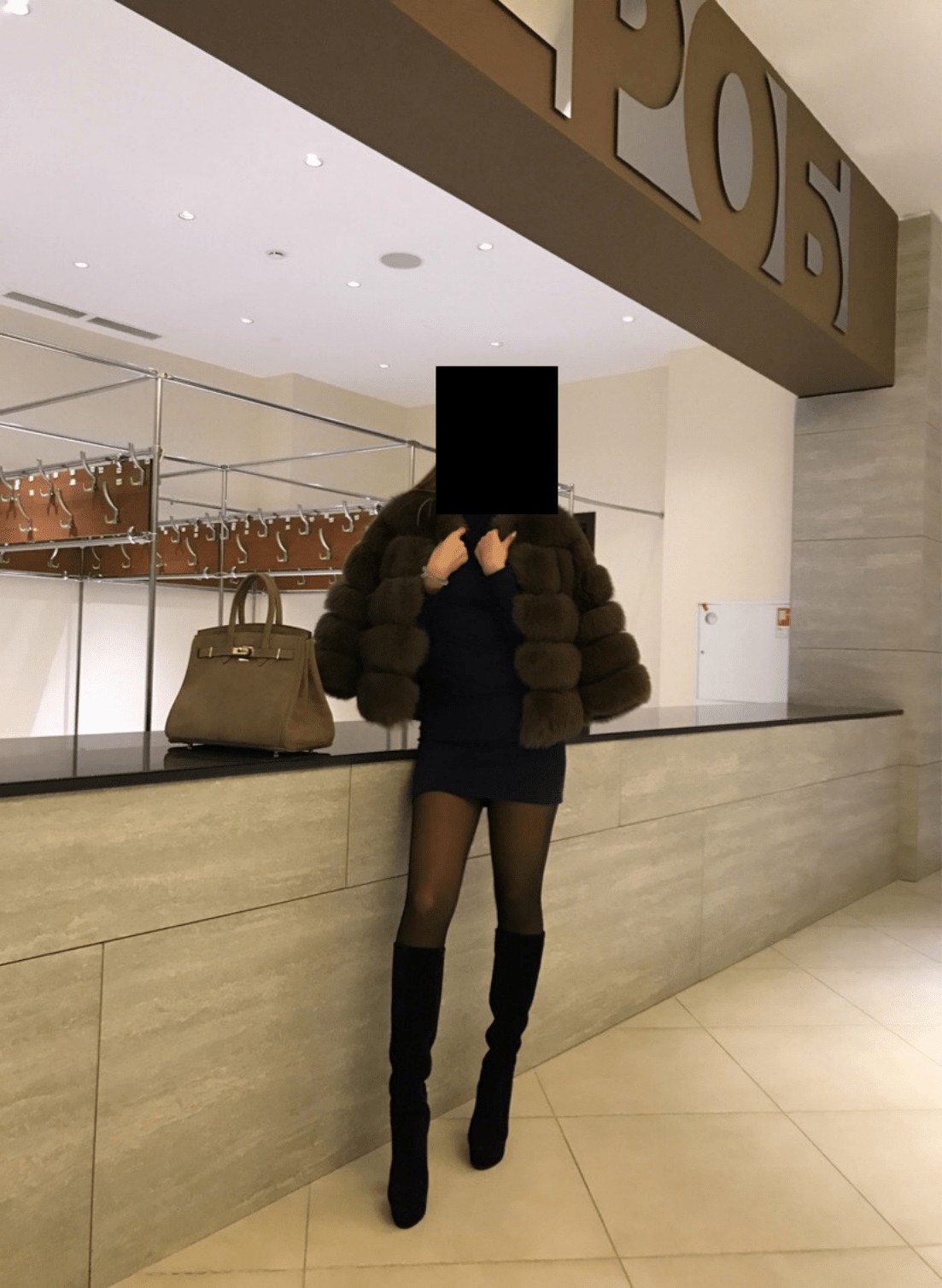 Девушка позирует у гардероба в неизвестном здании.