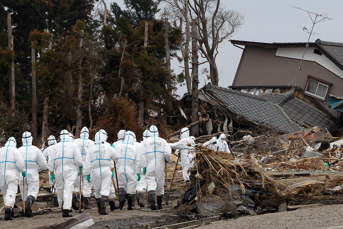 Спасатели ищут пропавших без вести в районе атомной электростанции Фукусима-Дайичи в городе Намиэ, префектура Фукусима, Япония, 12 марта 2011 года