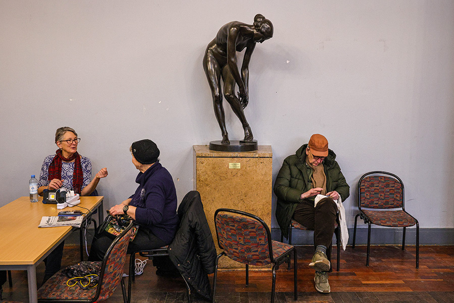 Люди заряжают телефоны в районном управлении Штеглиц-Целендорф во время отключения электроэнергии в Берлине