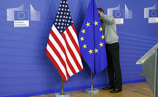 Служащий устанавливает флаги США и ЕС в штаб-квартире Еврокомиссии в Брюсселе