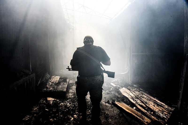 Ополченец ходит по разрушенному после обстрела рынку в Петровском районе Донецка. Снаряды попали также в находящиеся по соседству жилые дома.