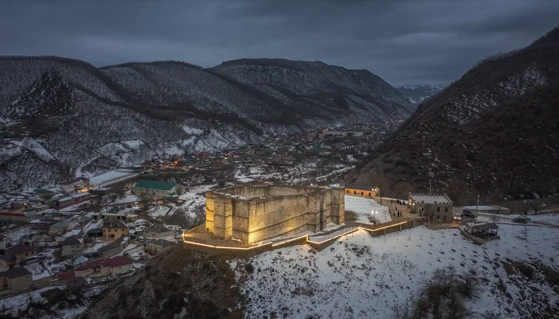 Крепость семи братьев и одной сестры подсвечена в ночи: сюрреалистическое зрелище у подножия гор
