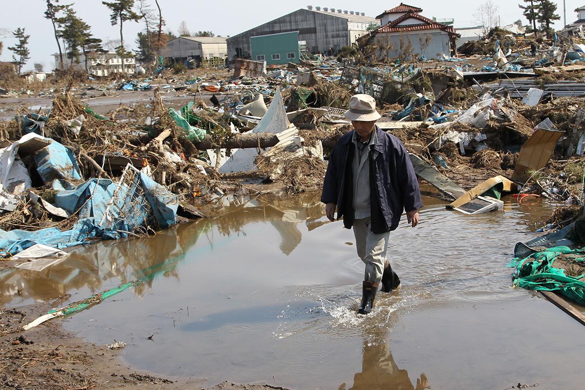 Люди идут среди разрушенных домов в префектуре Мияги, Япония, 13 марта 2011 года