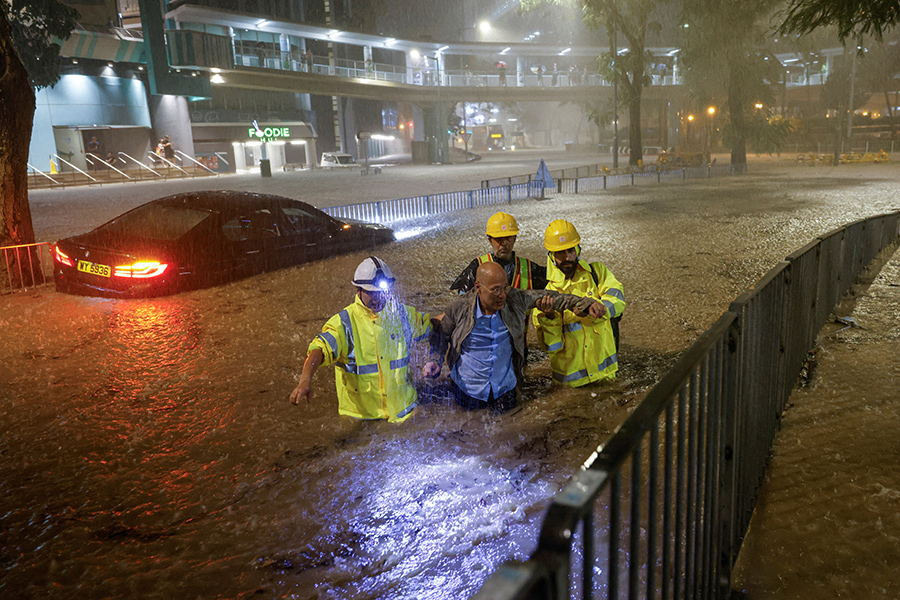 Рабочие помогают выбраться застрявшему из-за наводнения водителю в Гонконге