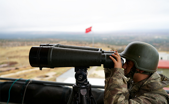 Турецкий солдат смотрит в бинокль на границе Турции и Сирии


