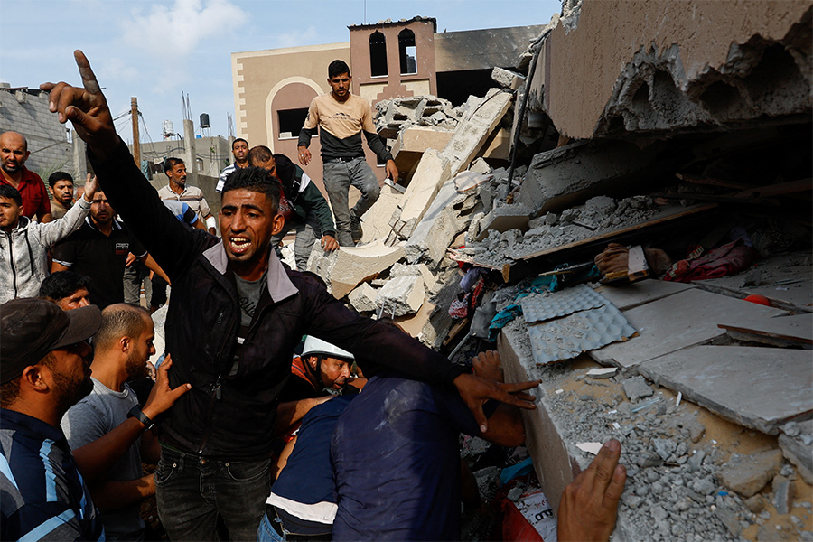 Палестинцы у развалин дома в городе Хан-Юнис после удара со стороны Израиля.

