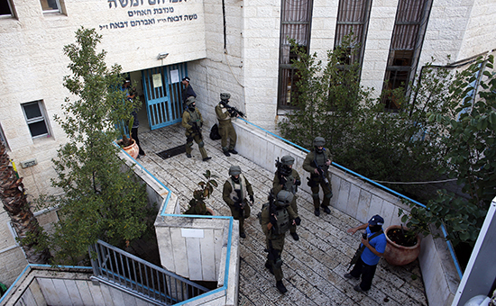 Сотрудники израильской службы безопасности осматривают территорию рядом с синагогой, где произошла трагедия