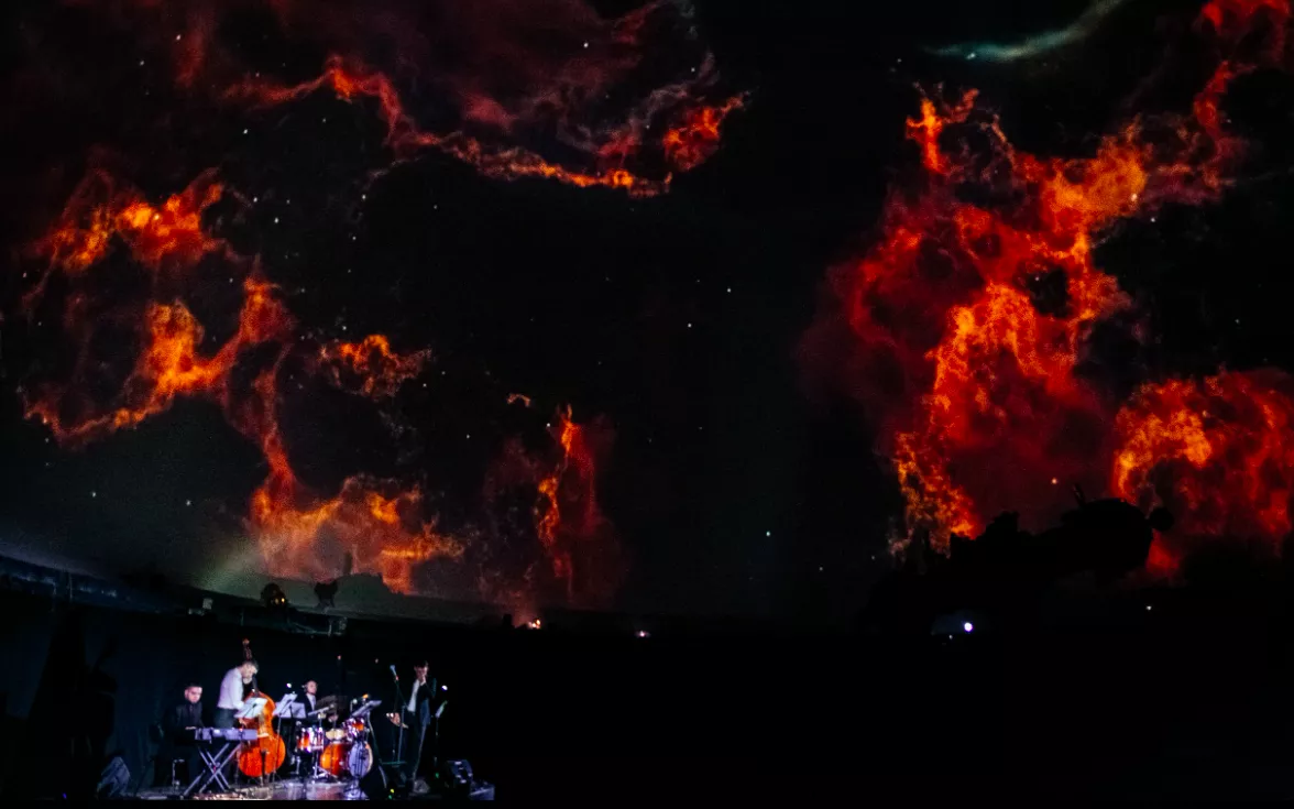 Музыканты под куполом планетария с проекцией фотографий из глубин космоса