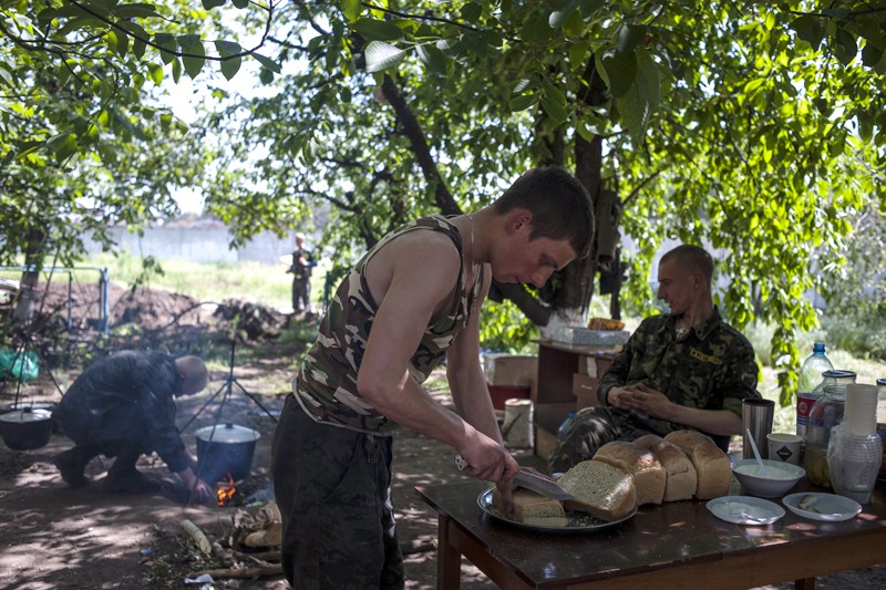 Боец Национальной гвардии Украины готовится к обеду в армейском лагере в окрестностях Славянска. Украинская армия осаждает город с конца апреля, но административные здания по-прежнему находятся в руках ополченцев. 