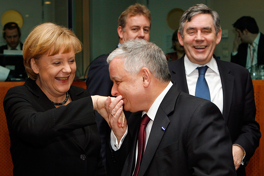19 марта 2009 года. Премьер-министр Великобритании Гордон Браун (справа) смотрит, как&nbsp;президент Польши Лех Качиньский целует руку канцлеру Германии Ангеле Меркель.
