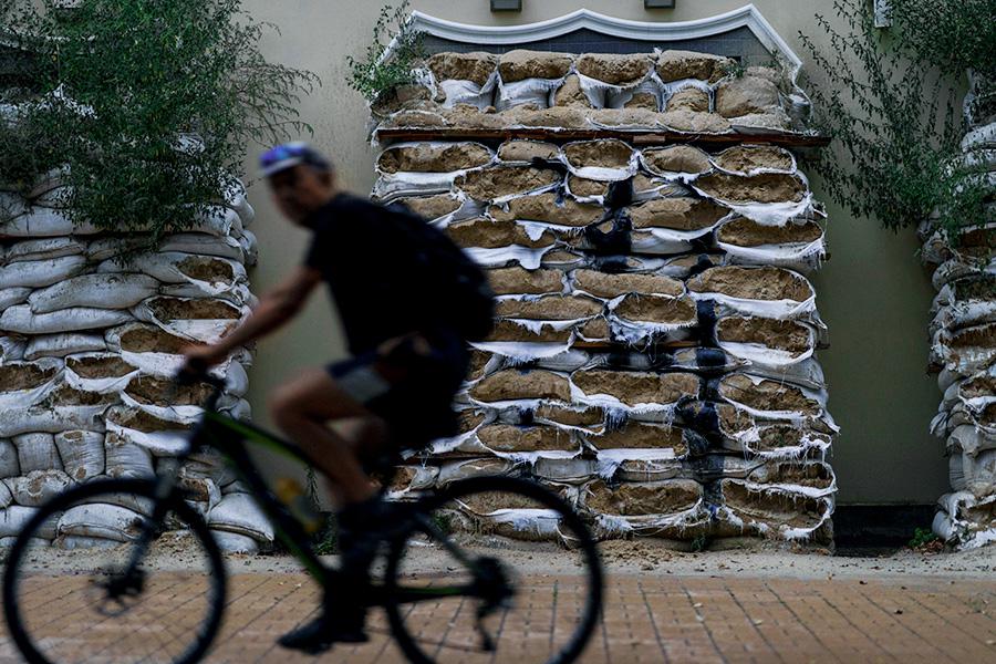 Житель Дружковки проезжает на велосипеде возле окон ресторана, закрытых мешками с песком от обстрелов, 19 августа 2022 года