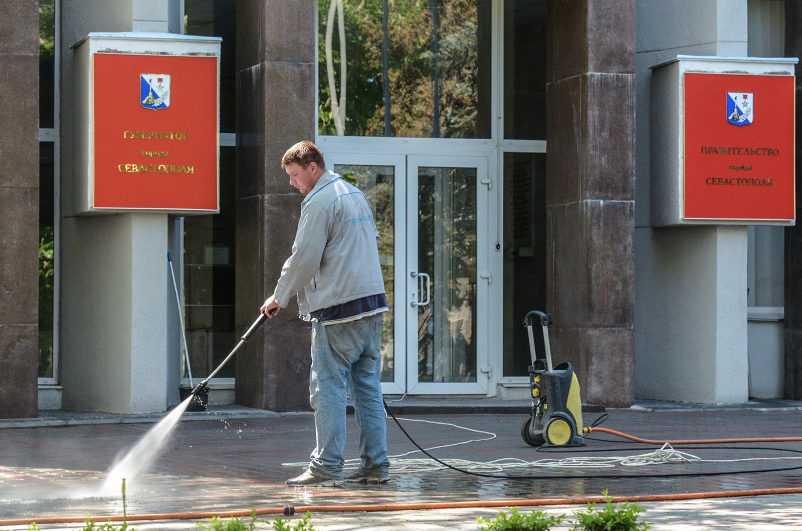 А сотрудники ЖКХ моют тротуары перед зданием городской администрации