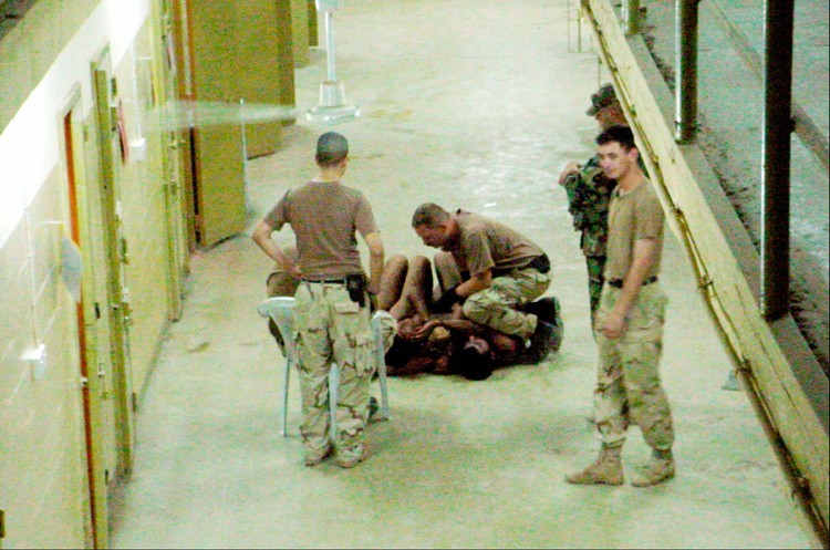 Неустановленный солдат армии США (в центре) на телах обнаженных заключенных в тюрьме "Абу-Грейб". Дата съемки неизвестна.