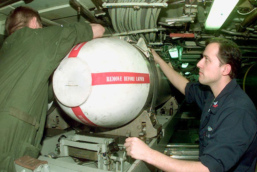 На борту ударной подводной лодки класса «Лос-Анджелес» USS Norfolk военные закрепляют ракетную капсулу «Томагавк» в торпедном отсеке лодки, 1 Апреля 1999 Года
