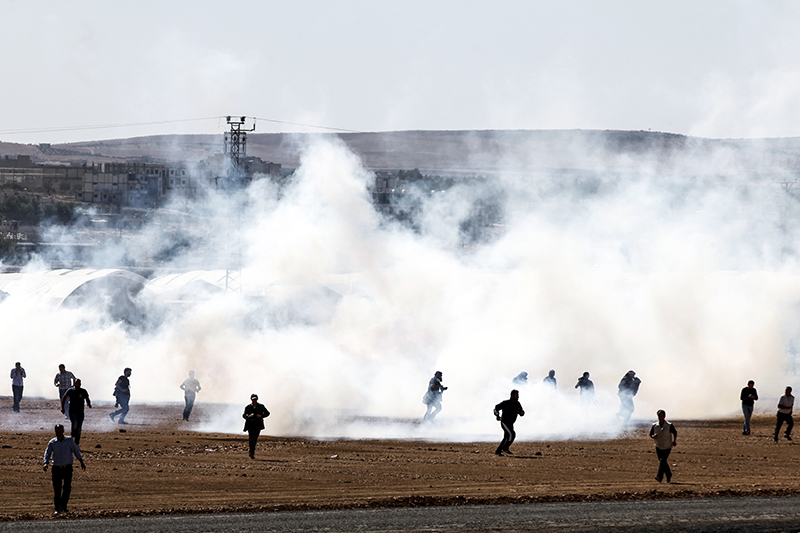 Протестующие в городе Шанлыурфа бегут от слезоточивого газа, распыляемого полицией при разгоне демонстрации.