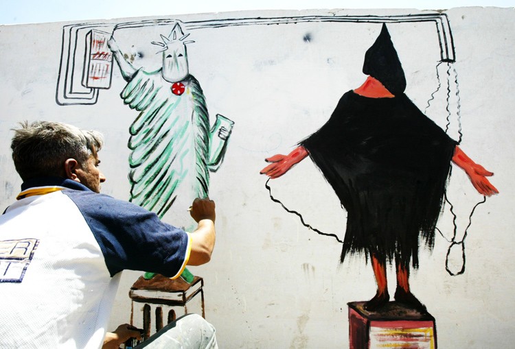Иракский художник Салахаддин ал-Саллат создает граффити, изображающее казнь узника "Абу-Грейб", на стене дома в районе Аль-Садр. Район населен шиитами, здесь живет наибольшее число сторонников радикального исламского лидера Муктады ас-Садра.
