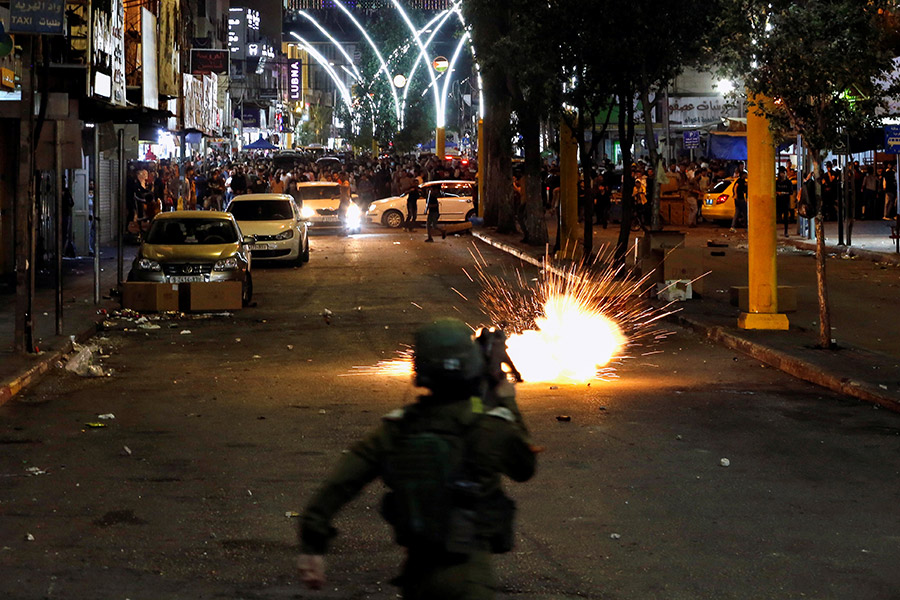 Палестинский демонстрант бросает камни в израильского полицейского в Хевроне. 11 мая в этом городе прошли антиизраильские акции протеста