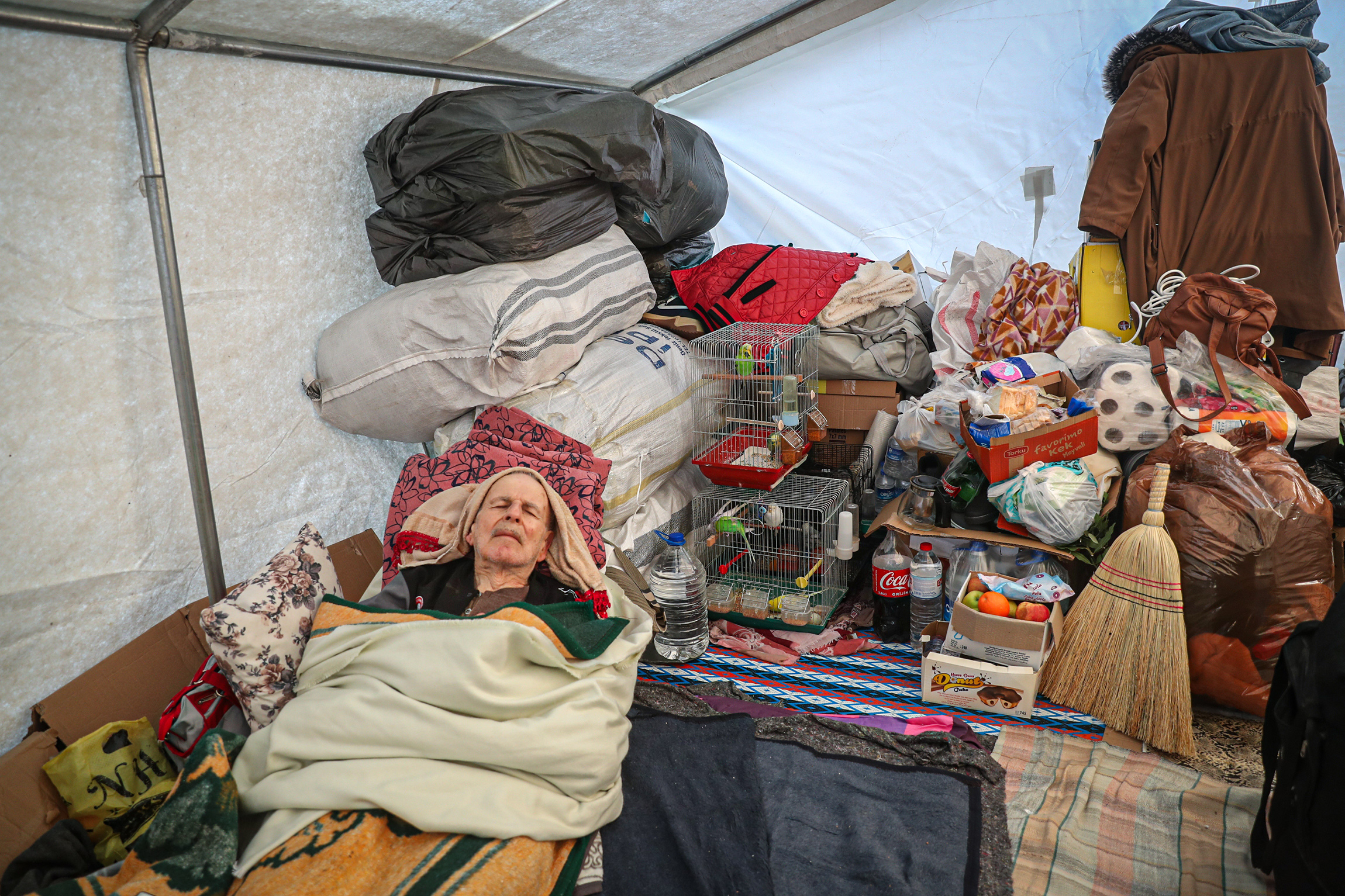 Мужчина, выживший после землетрясения, живет с семьей в палатке в провинции Хатай. Чтобы помочь людям адаптироваться и справиться с гибелью близких, в зоне землетрясения работают более 2 тыс. сотрудников психолого-социальной службы.