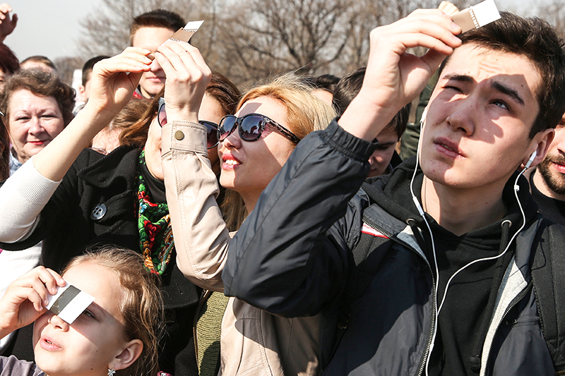 Жители Москвы наблюдают за солнечным затмением в Парке им. Горького