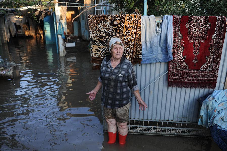 Жительница Крымска во дворе жилого дома, пострадавшего от наводнения, 2012 год