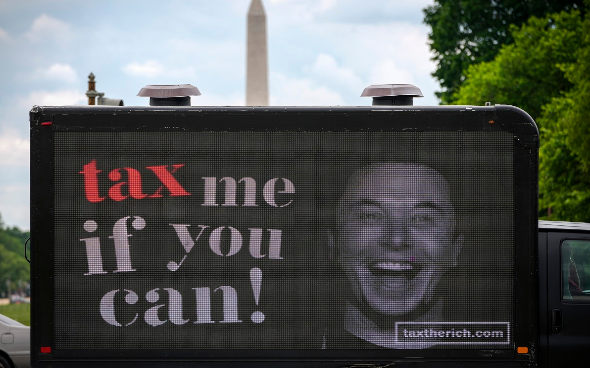 Рекламный щит, призывающий к повышению налогов на сверхбогатых, изображает бизнесмена-миллиардера Илона Маска. Снято возле Капитолия в Вашингтоне, 17 мая 2021 года