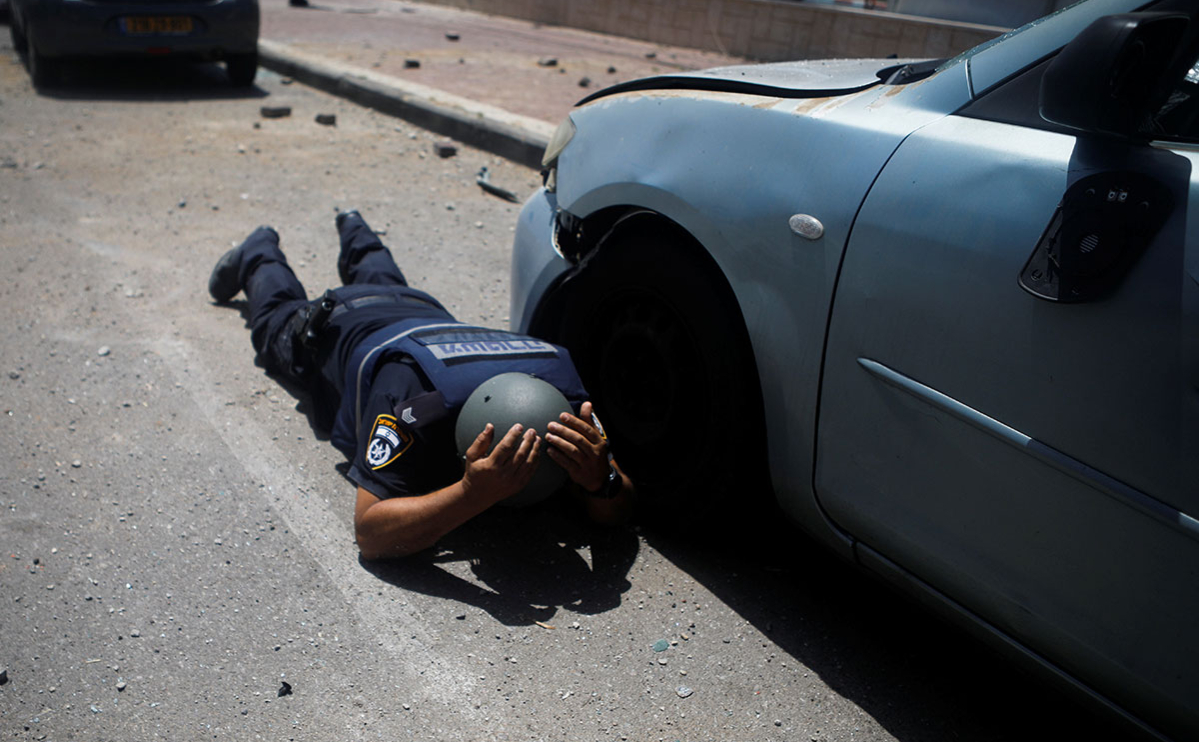 Израильский полицейский укрывается под звуками сирен, предупреждающих о приближающихся ракетах, запущенных из сектора Газа, в Ашкелоне, на юге Израиля, 11 мая 2021 года.
&nbsp;