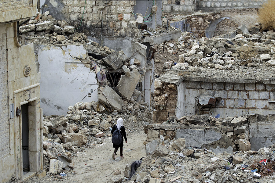 Сирийская школьница идет по разрушенному району Идлиба