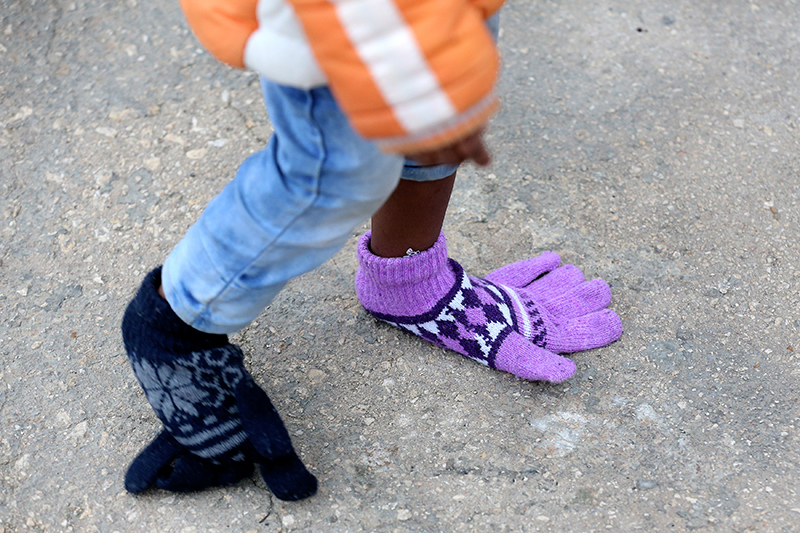 Ребенок с перчатками на ногах на итальянском острове Сицилия, куда девочка прибыла вместе со своей матерью из Северной Африки
