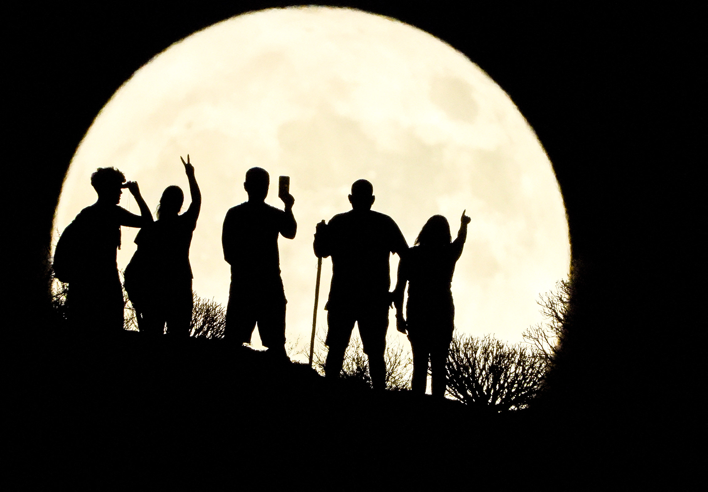 Люди на фоне полной луны в городе Аргинегин, Испания