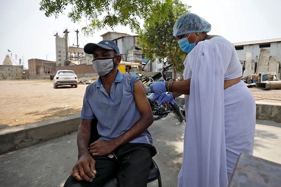 Работник рисового завода получает дозу местной вакцины Covishield около рабочего места в деревне Бавла, Индия, 13 апреля
