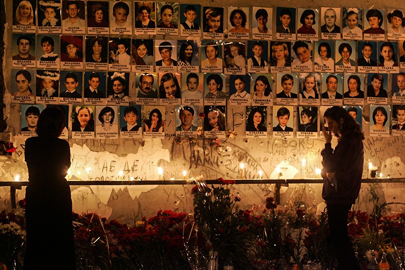 Первая годовщина бесланской трагедии - женщина стоит перед стеной с фотографиями погибших в сентябре 2004 года 