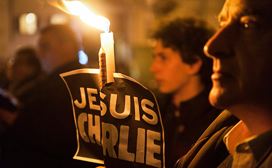 Человек держит свечу во время акции в знак солидарности с жертвами вчерашнего теракта в Париже