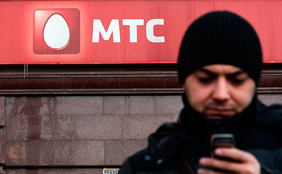 Мужчина с&nbsp;телефоном стоит у офиса компании оператора мобильной связи МТС в&nbsp;Москве
