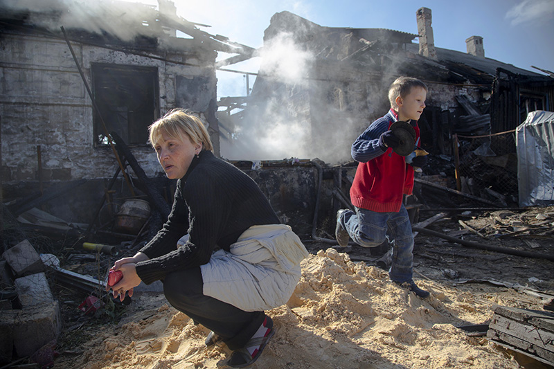 Жительница Донецка с сыном возле разрушенного во время обстрела дома