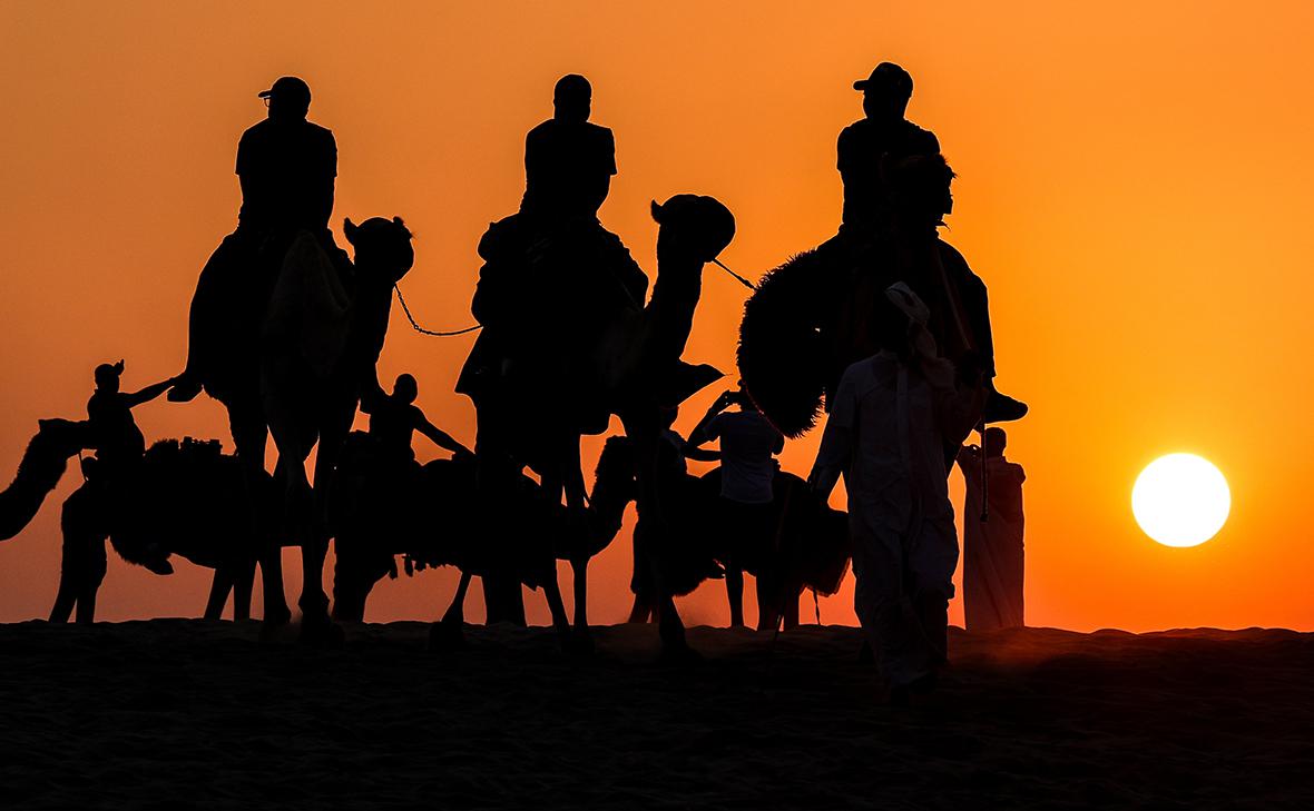 Туристы во время сафари на верблюдах в пустыне Катара