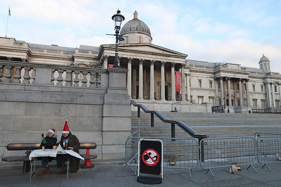 Жители Лондона Ник и Чарли разговаривают с родственниками по телефону во время завтрака на Трафальгарской площади 25 декабря. Пара решила пообедать на свежем воздухе после того, как их запланированная поездка к семье была отменена из-за ограничений