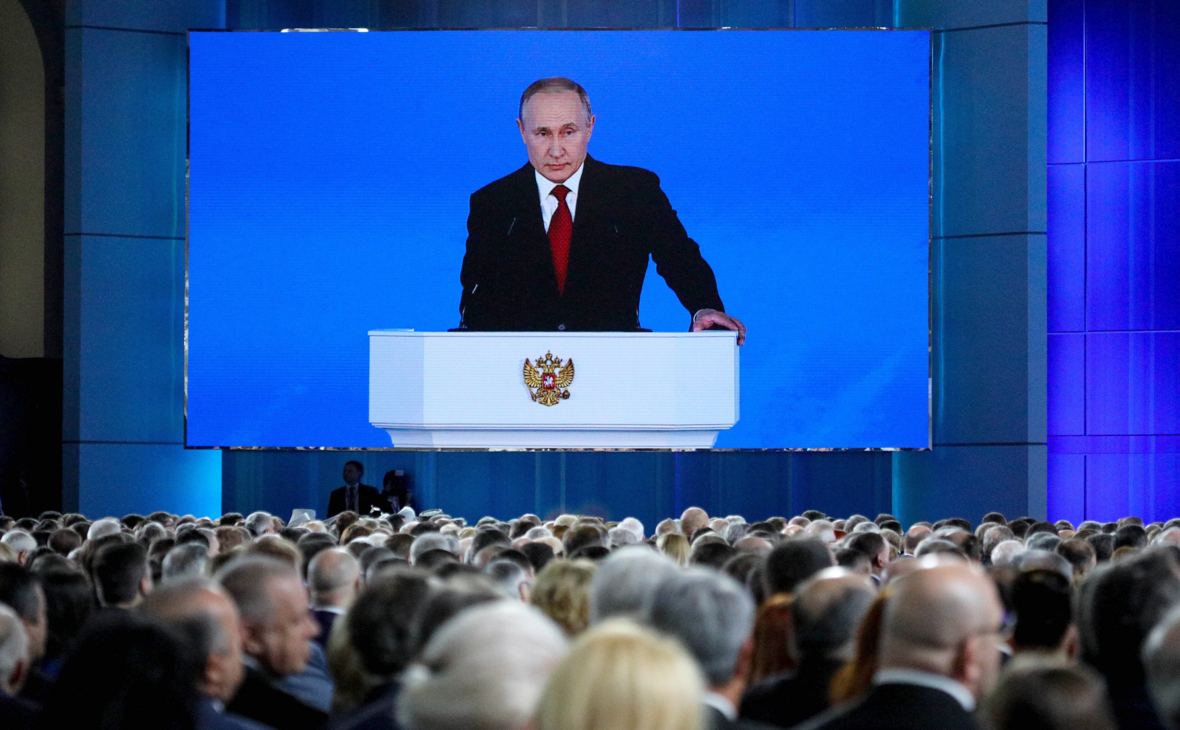 Владимир Путин (на экране) во время выступления с ежегодным посланием к Федеральному Собранию РФ