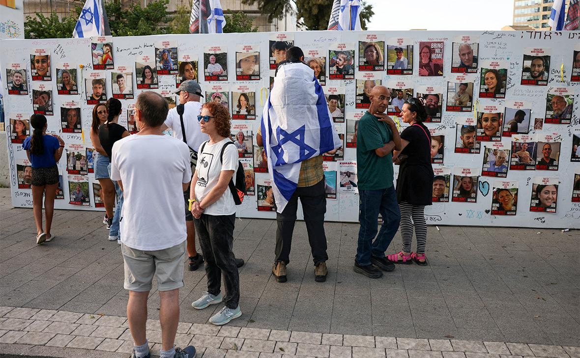 Люди стоят у стены с фотографиями заложников, удерживаемых движением ХАМАС, Тель-Авив, Израиль
