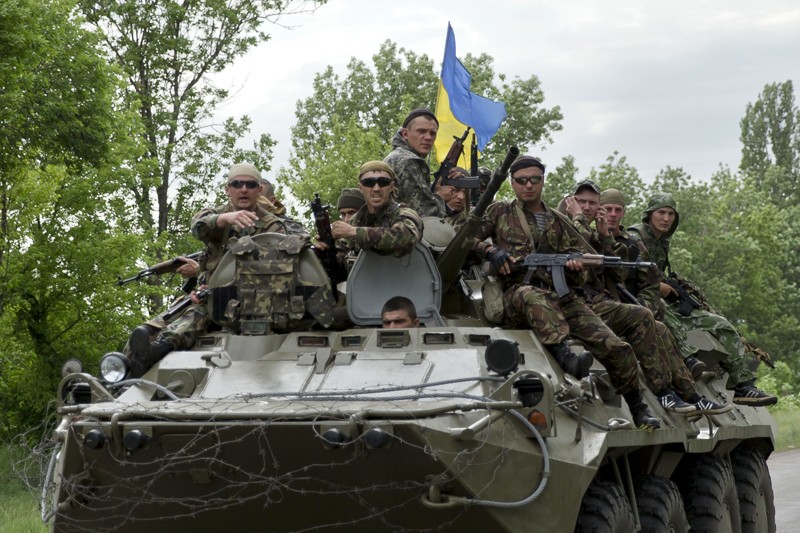 Украинские солдаты сидят на БТР, покидающем украинский КПП, который подвергся нападению антиправительственными активистами около села Благодатное. 