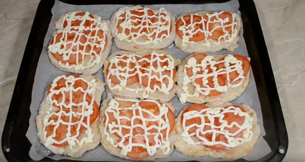 Положите на мясо лук и помидоры