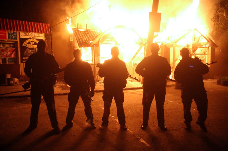 Антиправительственные боевики фотографируются перед горящим кафе после минометного обстрела около главной трассы, которая связывает Харьков и Славянск. 
