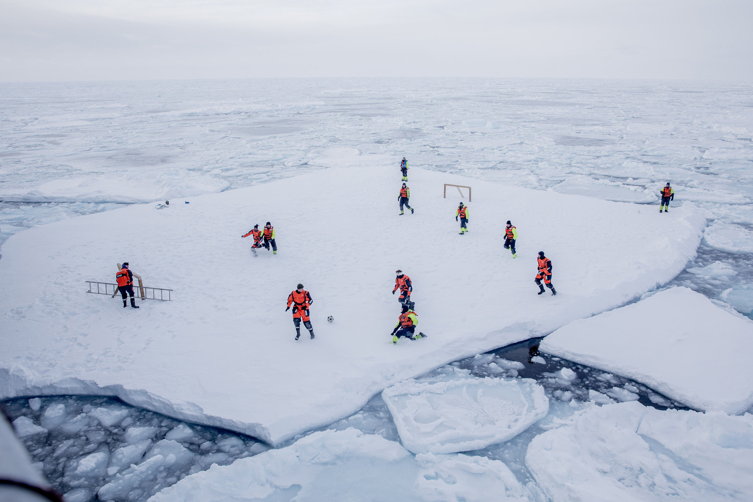 Март. Гренландия. Служащие норвежского военно-морского флота и ученые из Норвежского института морских исследований играют в футбол, пока вооруженная охрана защищает их от белых медведей
