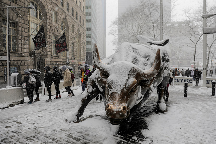 Пешеходы в районе Нью-Йоркской фондовой биржи около одного из символов города &mdash; скульптуры &laquo;Атакующий бык&raquo;