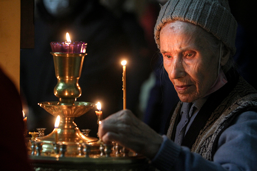 Женщина ставит свечку во время Рождественской службы в церкви в Грозном