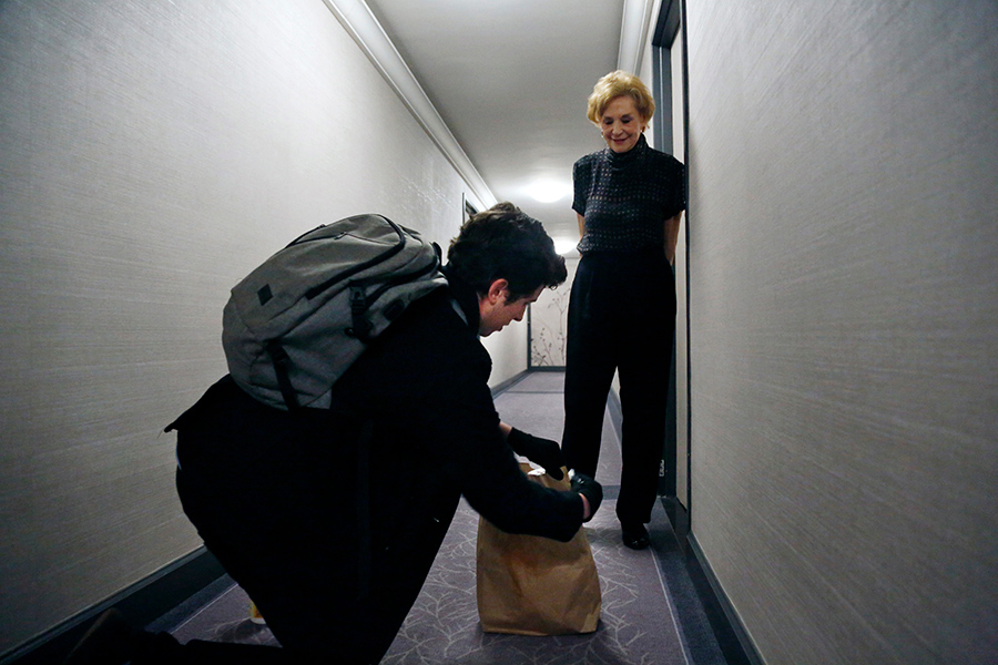 Молодой человек дезинфицирует пакет с покупками для женщины, находящейся в самоизоляции. Нью-Йорк, США​

