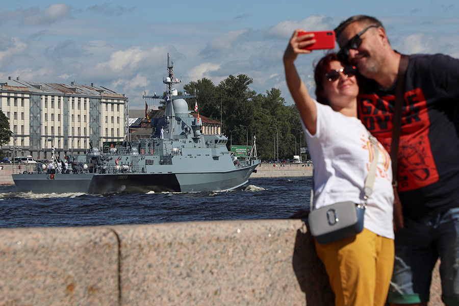 Люди в Санкт-Петербурге фотографируются на фоне проплывающего по Неве ракетного корабля &laquo;Советск&raquo;.