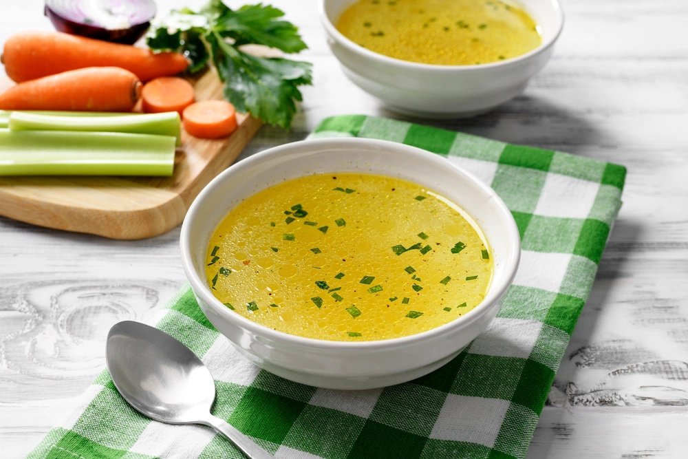 Куриный бульон подают с зеленью и сваренным вкрутую яйцом